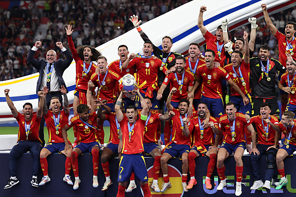 Auf dem Bild sieht man das spanische Fußball-Team über den Sieg jubeln. Alvaro Morata hält die Trophäe in den Händen.