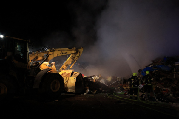 Auf dem Foto sieht man den Sperrmüll-Haufen. Feuerwehrleute löschen den Brand.