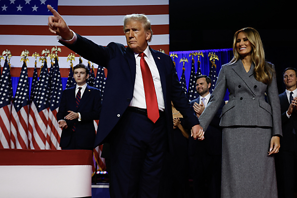 Auf dem Foto sieht man Donald Trump und seine Frau Melania bei seiner Siegesrede. Er deutet mit dem Finger in Richtung Zuschauer.