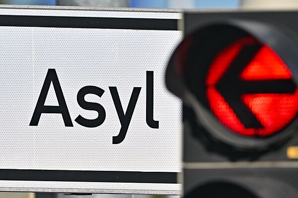 Auf dem Bild sieht man eine Pfeil-Ampel, die auf ein Asyl-Schild zeigt.