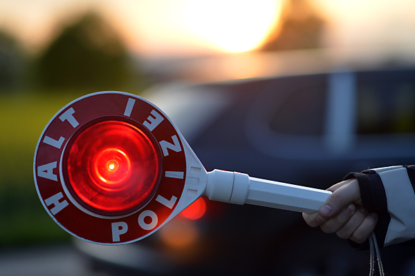 Auf dem Bild sieht man ein Polizei-Stoppschild, das in der Hand gehalten wird.