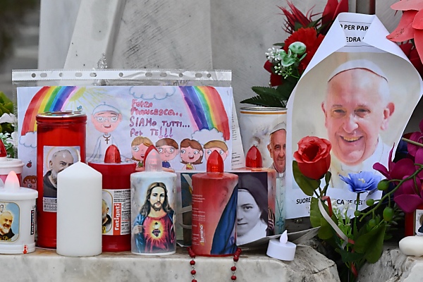 Auf dem Bild sieht man Kerzen, Blumen, eine Zeichnung und ein Bild von Papst Franziskus. Sie wurden vor dem Spital aufgestellt.