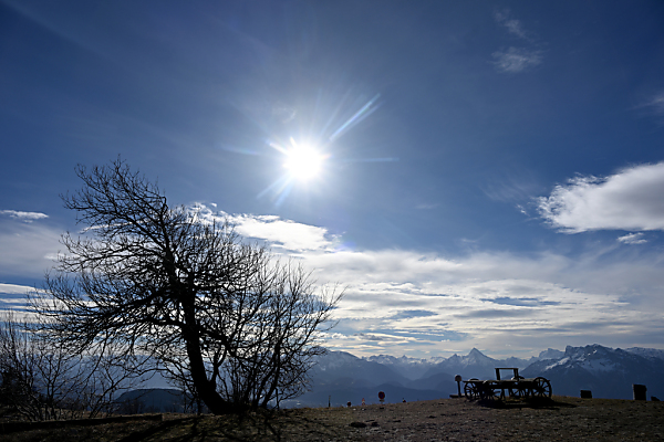 Auf dem Bild sieht man Sonne und Wolken über Bergen in Salzburg.