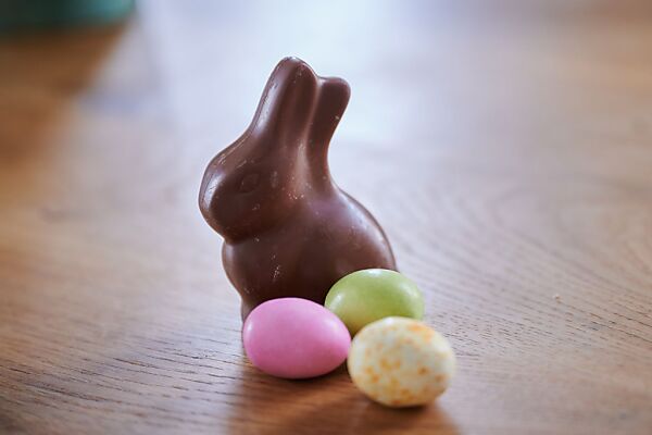 Auf dem Bild sieht man einen Schokolade-Osterhasen und Ostereier.
