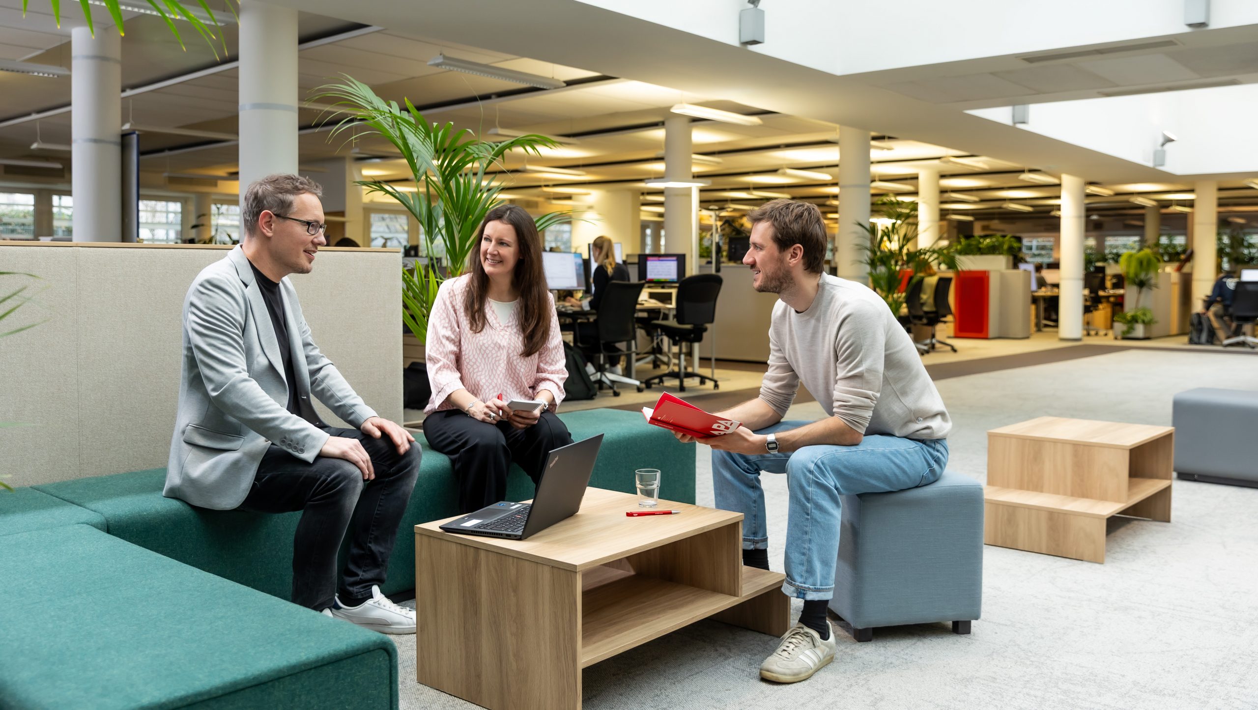 Ein Foto aus dem Newsroom, zwei Kollegen und eine Kollegin sitzen um einen Tisch.
