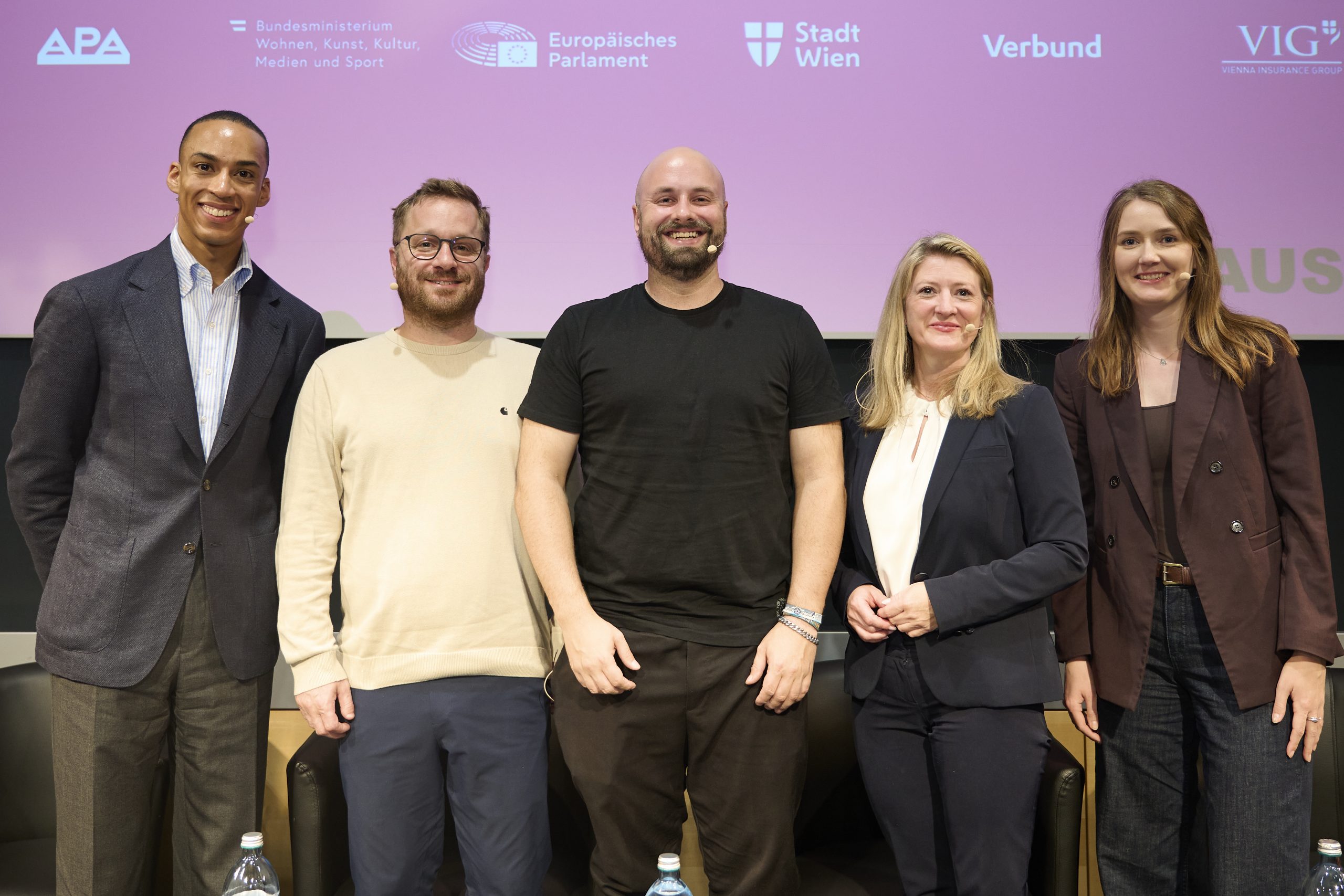 Drei Männer und zwei Frauen posieren für ein Foto und lächeln