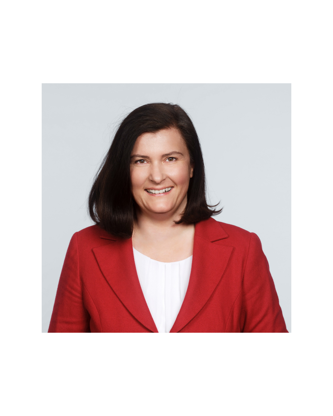 Eine Frau mit einem roten Blazer lächelt in die Kamera